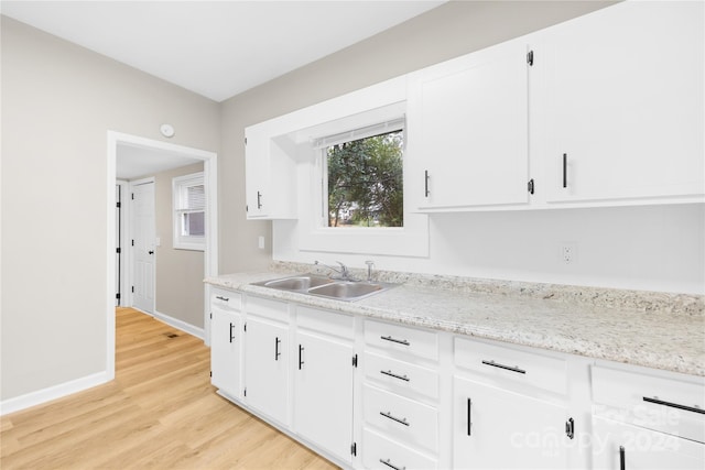 kitchen with white cabinets, light hardwood / wood-style floors, and sink