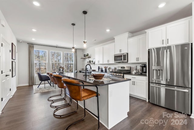 kitchen with white cabinets, dark hardwood / wood-style flooring, an island with sink, and stainless steel appliances