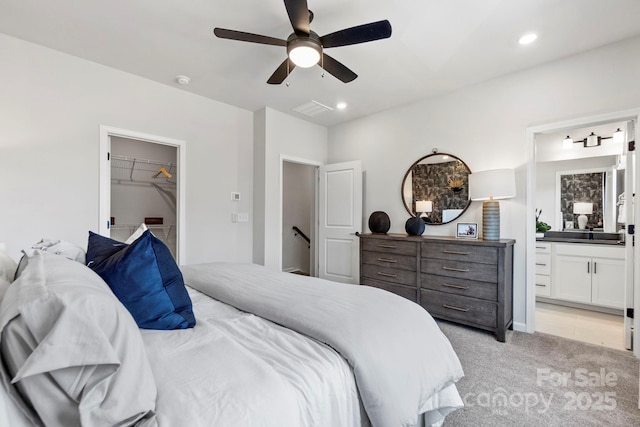 carpeted bedroom with ceiling fan, connected bathroom, and a walk in closet