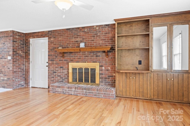 unfurnished living room with a fireplace, light wood-type flooring, ceiling fan, and crown molding