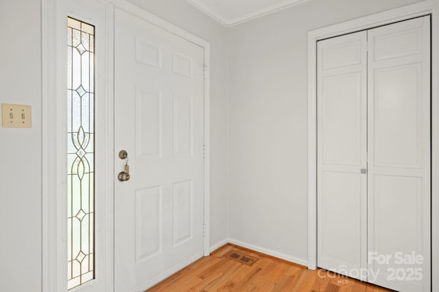 foyer with light wood-style flooring, visible vents, and baseboards