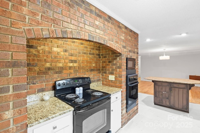 kitchen featuring black appliances, light stone counters, brick wall, and white cabinets