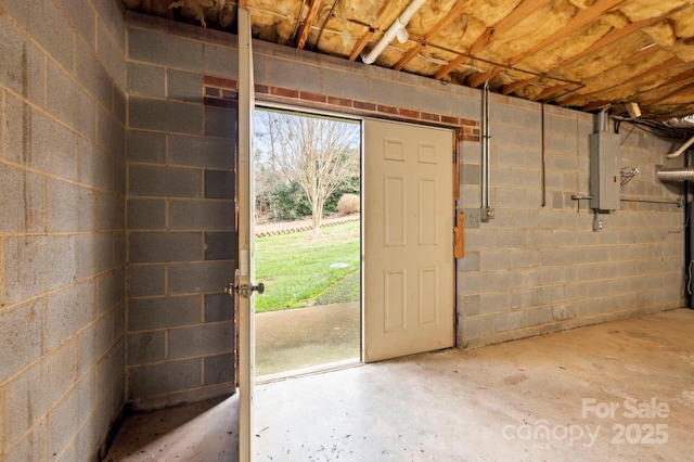 below grade area featuring concrete block wall and electric panel