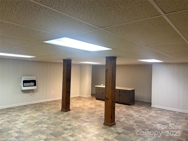 finished basement with heating unit, baseboards, and a paneled ceiling