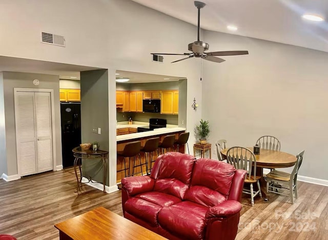 living room with ceiling fan, light hardwood / wood-style floors, and high vaulted ceiling