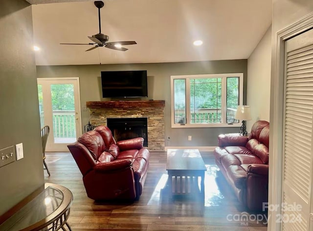 living room with hardwood / wood-style floors, ceiling fan, and a stone fireplace