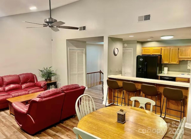 dining space featuring ceiling fan, high vaulted ceiling, and light hardwood / wood-style flooring