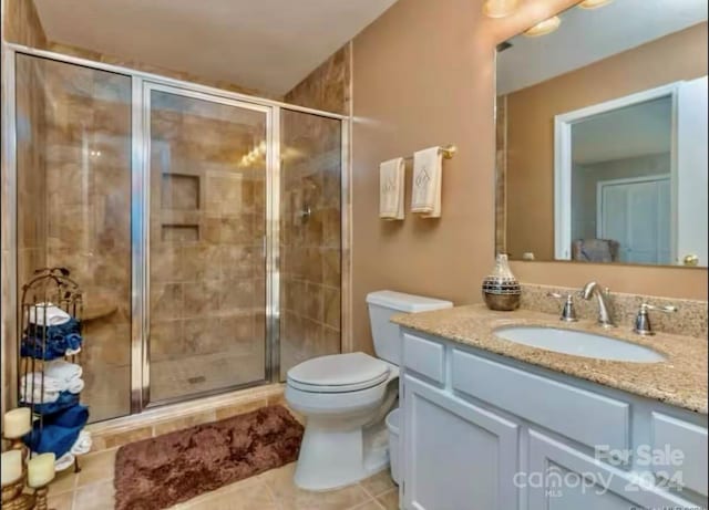 bathroom with tile patterned floors, vanity, toilet, and walk in shower