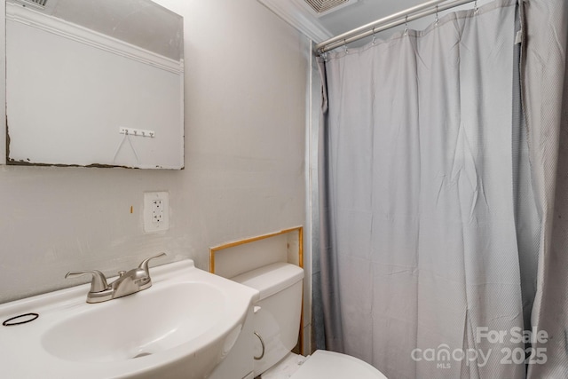 bathroom featuring toilet, walk in shower, crown molding, and sink