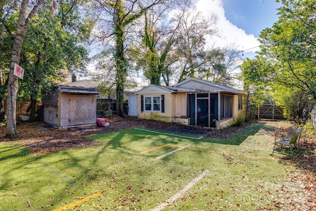 rear view of property featuring a lawn, a sunroom, and a shed