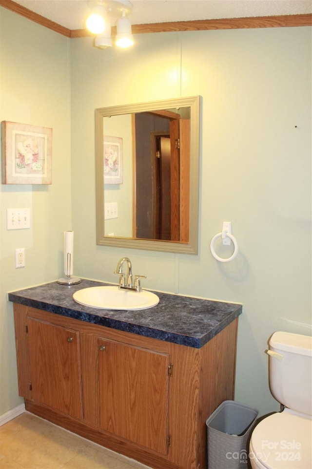 bathroom with vanity, toilet, and ornamental molding