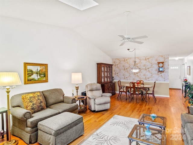 living room with ceiling fan, wood-type flooring, and lofted ceiling with skylight