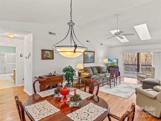 dining space with ceiling fan, light wood-type flooring, and lofted ceiling with skylight