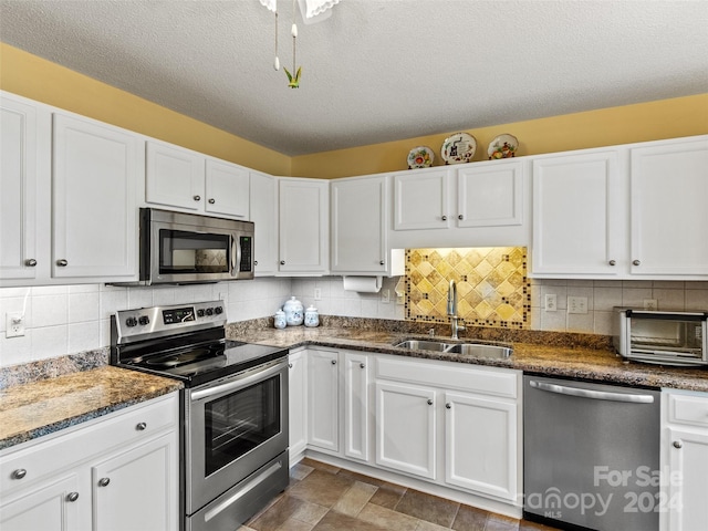 kitchen featuring white cabinetry, sink, backsplash, a textured ceiling, and appliances with stainless steel finishes