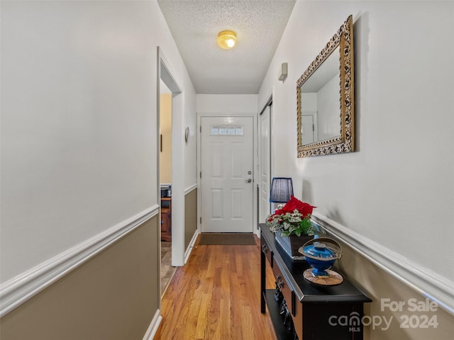 corridor featuring light wood-type flooring and a textured ceiling