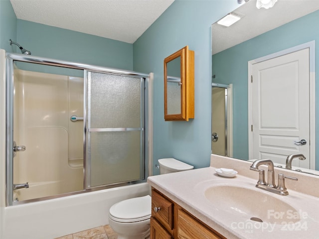 full bathroom with vanity, a textured ceiling, enclosed tub / shower combo, tile patterned flooring, and toilet