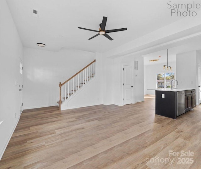 unfurnished living room featuring ceiling fan, light wood-type flooring, and sink