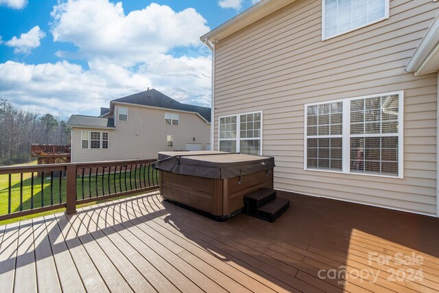 wooden deck with a lawn and a hot tub