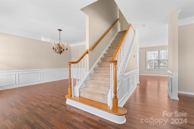 staircase with hardwood / wood-style flooring, an inviting chandelier, and crown molding