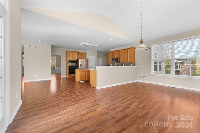 kitchen with appliances with stainless steel finishes, dark hardwood / wood-style flooring, decorative light fixtures, and vaulted ceiling