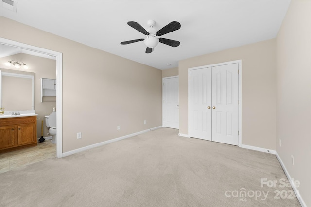 unfurnished bedroom with ceiling fan, light colored carpet, and connected bathroom