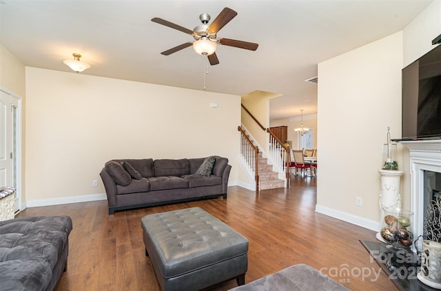 living room with ceiling fan with notable chandelier and dark wood-type flooring