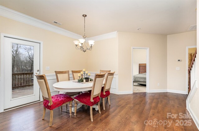 dining room with dark hardwood / wood-style floors, crown molding, and a chandelier