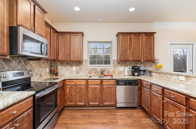 kitchen featuring light stone countertops, sink, stainless steel appliances, tasteful backsplash, and hardwood / wood-style floors