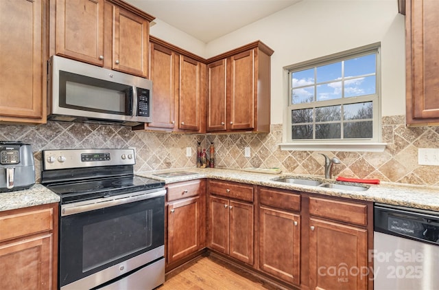 kitchen featuring appliances with stainless steel finishes, light stone counters, and sink