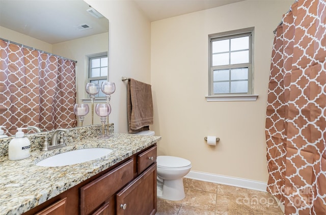 bathroom featuring a wealth of natural light, vanity, and toilet