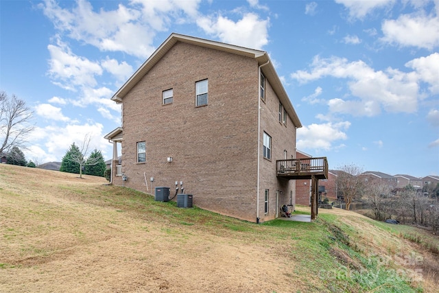 view of side of home with a yard, cooling unit, and a deck