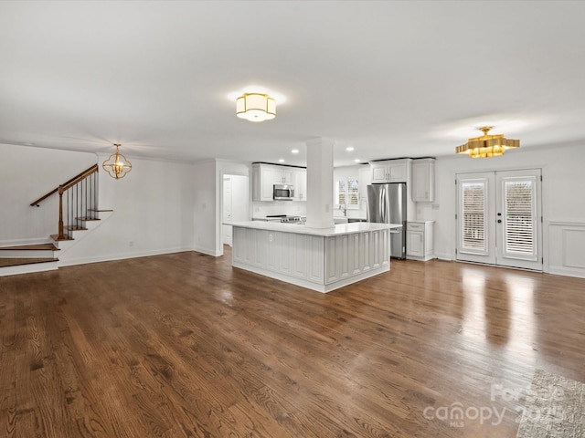 unfurnished living room featuring french doors, hardwood / wood-style flooring, an inviting chandelier, and a healthy amount of sunlight