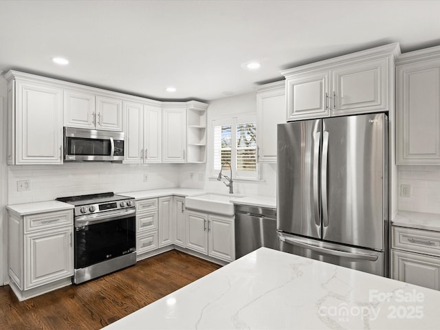 kitchen featuring appliances with stainless steel finishes, tasteful backsplash, sink, dark hardwood / wood-style floors, and white cabinetry