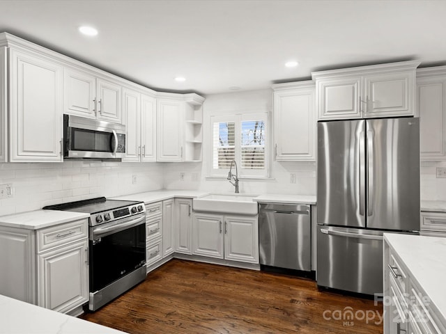 kitchen with backsplash, stainless steel appliances, sink, white cabinets, and dark hardwood / wood-style floors