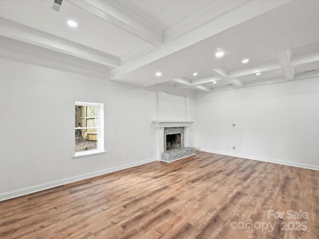 unfurnished living room featuring beamed ceiling, a stone fireplace, wood-type flooring, and coffered ceiling