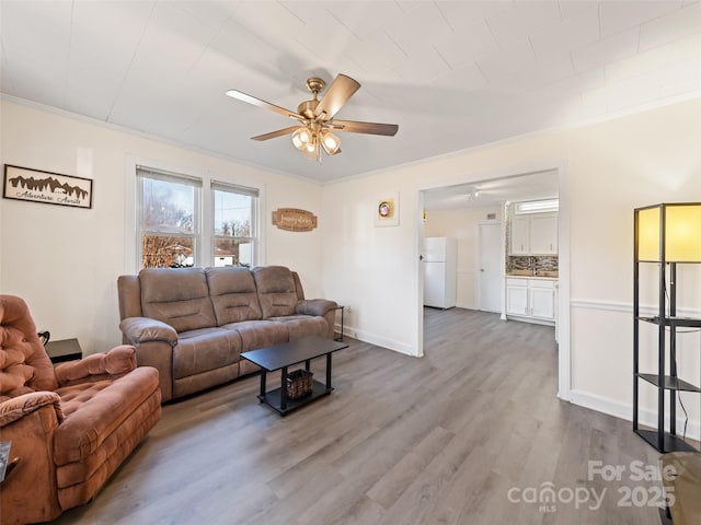 living room with hardwood / wood-style flooring, ceiling fan, and crown molding