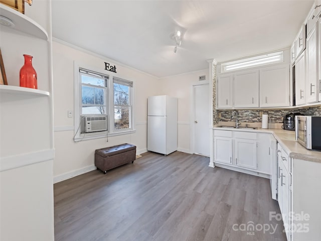 kitchen with sink, white refrigerator, backsplash, cooling unit, and white cabinets