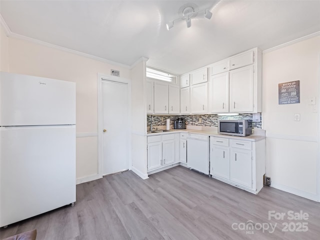 kitchen featuring white appliances, white cabinets, sink, decorative backsplash, and light wood-type flooring