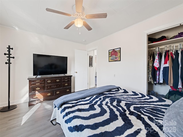 bedroom with hardwood / wood-style flooring, ceiling fan, ornamental molding, and a closet