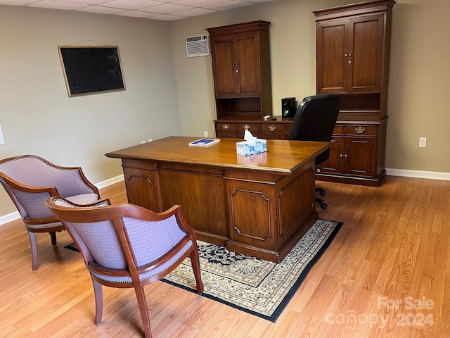 office featuring an AC wall unit, a paneled ceiling, and light hardwood / wood-style floors