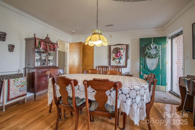 dining area with hardwood / wood-style flooring and crown molding