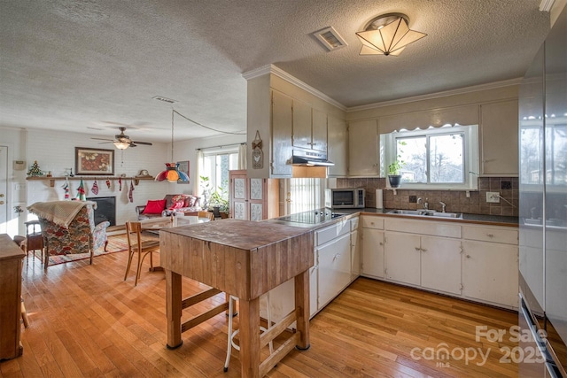 kitchen featuring black electric cooktop, sink, white cabinets, and a textured ceiling