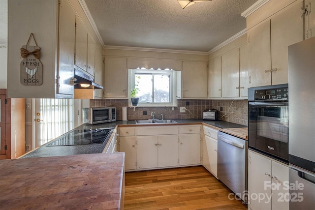 kitchen featuring decorative backsplash, light wood-type flooring, a textured ceiling, sink, and black appliances