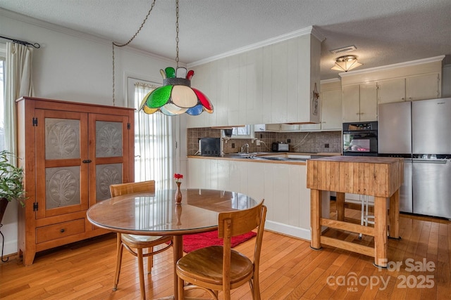 dining room featuring plenty of natural light, crown molding, a textured ceiling, and light hardwood / wood-style flooring