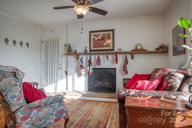 living room with a fireplace, wood-type flooring, ceiling fan, and crown molding