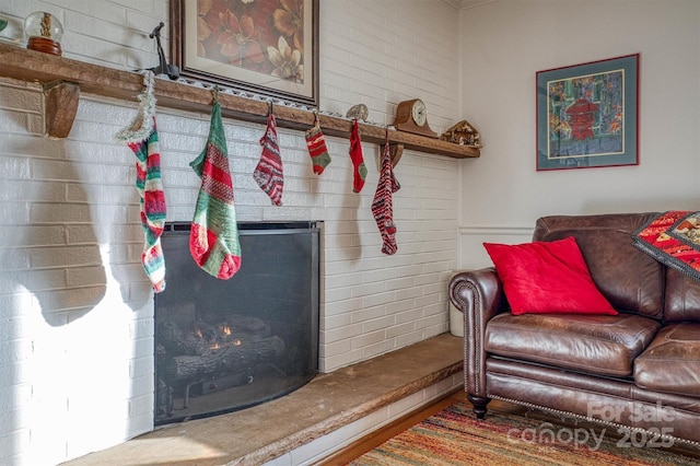 living room featuring a brick fireplace and brick wall