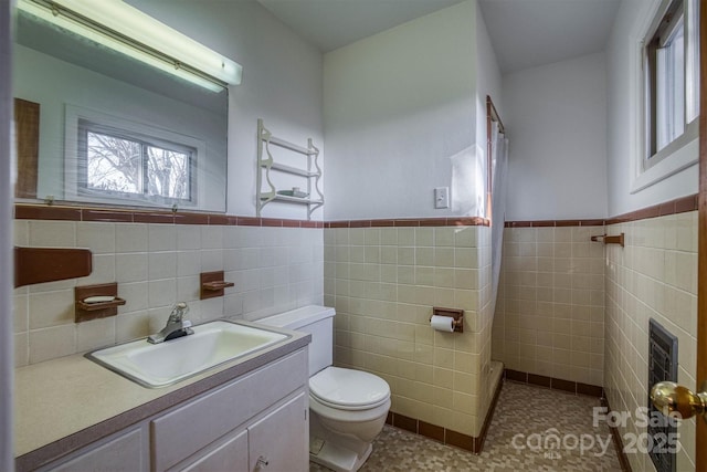 bathroom featuring tile patterned floors, vanity, toilet, and tile walls