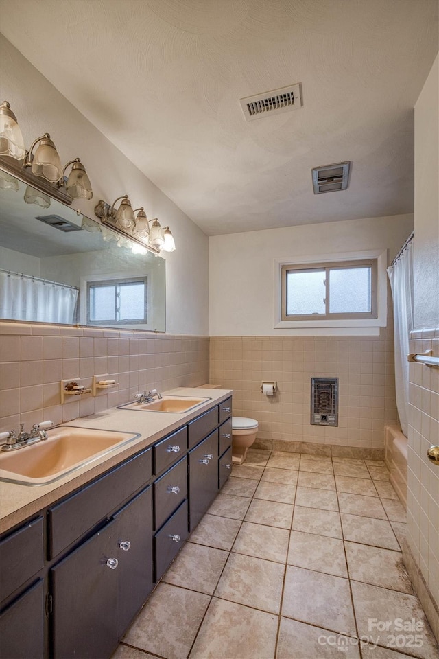 full bathroom featuring vanity, tile patterned floors, toilet, tile walls, and heating unit