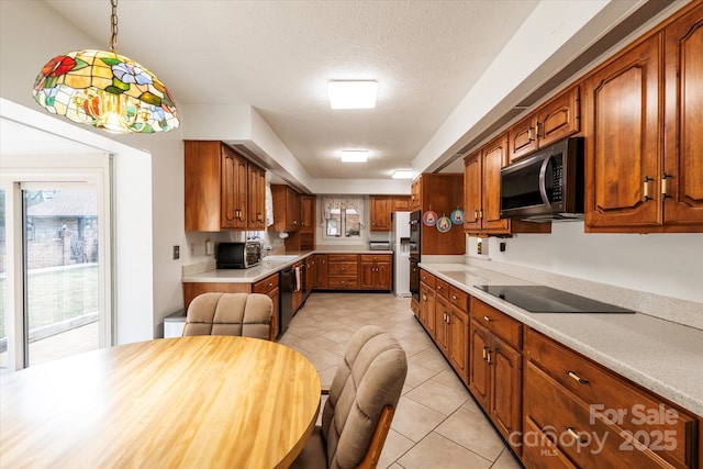 kitchen with decorative light fixtures, black appliances, sink, a textured ceiling, and light tile patterned floors