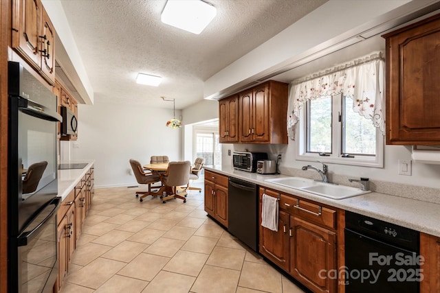 kitchen featuring light tile patterned flooring, hanging light fixtures, a textured ceiling, black appliances, and sink